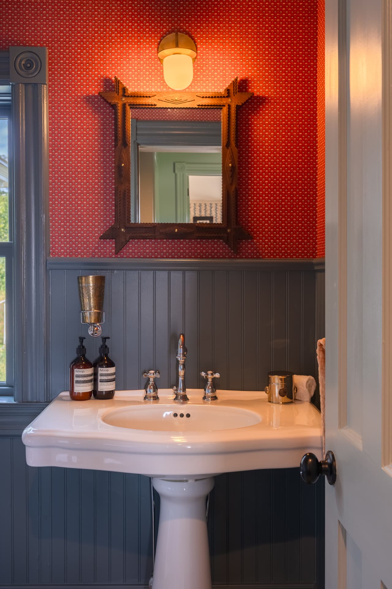 Powder room with red wallpaper and pedestal sink