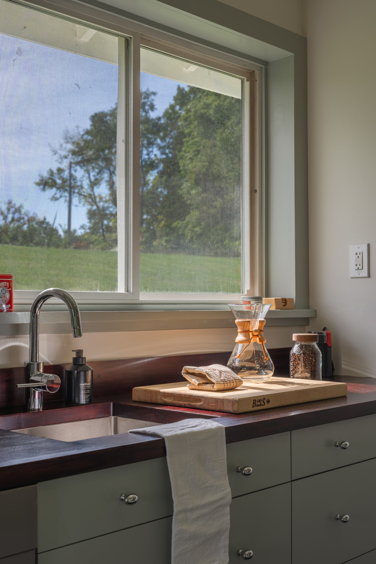 Cabin kitchen sink beneath a window to the lawn