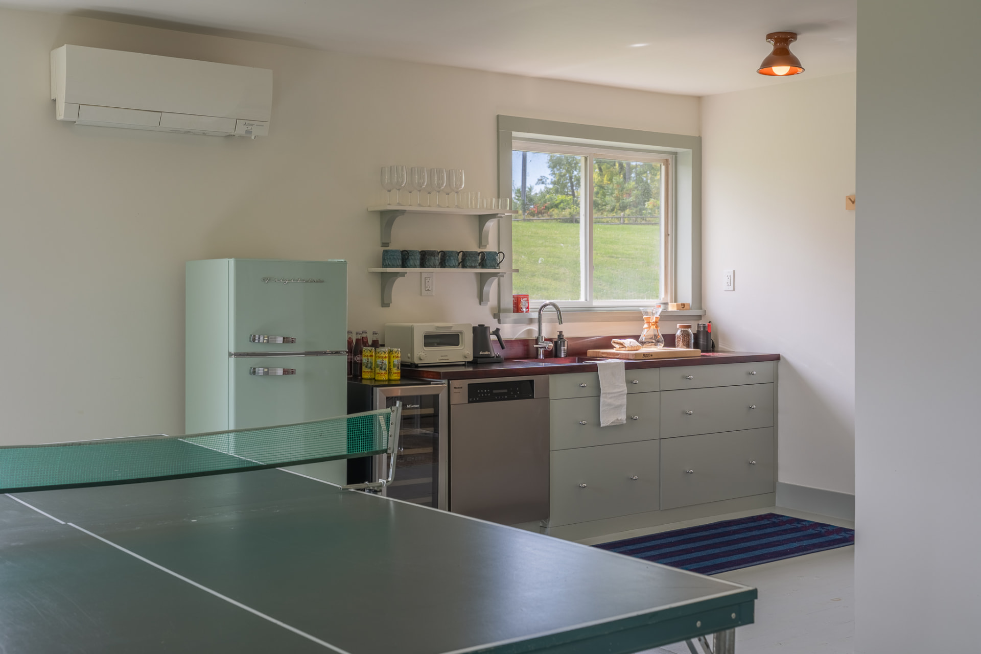 The Cabin kitchen and games room, with a mint-green refrigerator, sage cabinets and a ping-pong table