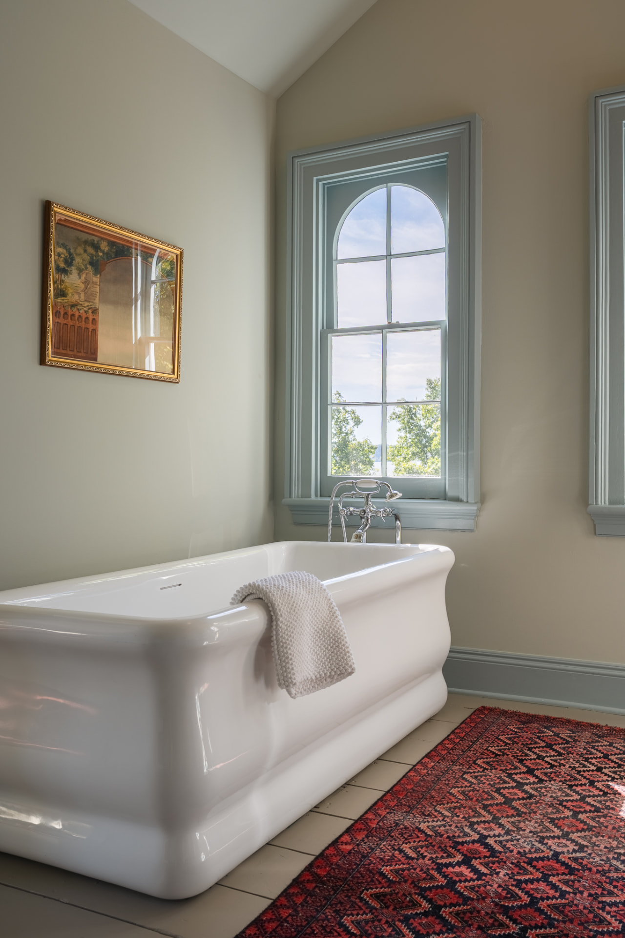 Bathtub beside an arched window with river light